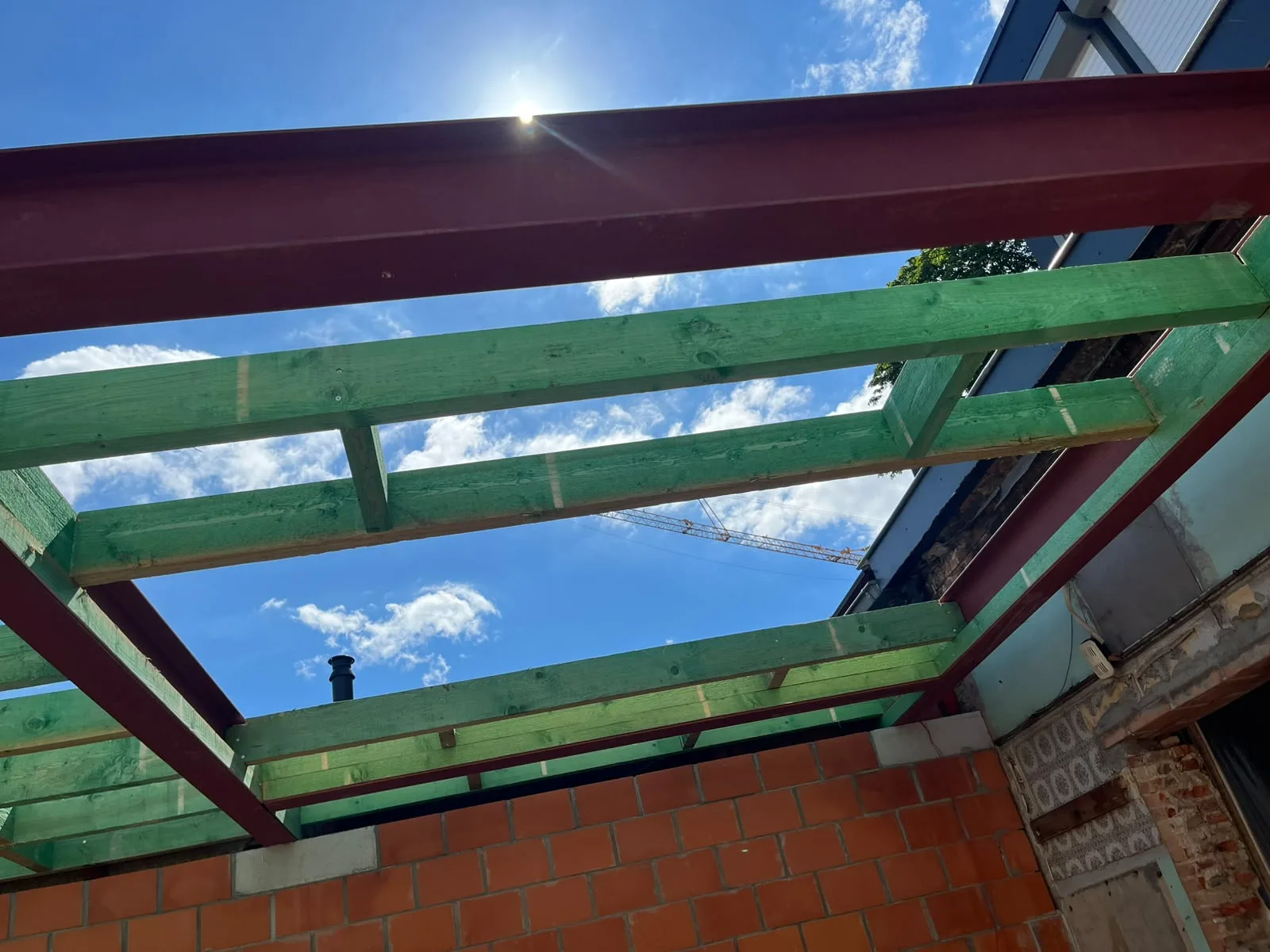 Nieuwe houten kepers op stalen liggers boven een uitbouw