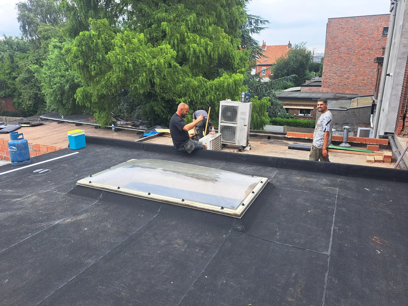 Afgewerkt plat dak met lichtkoepel en het team aan het werk