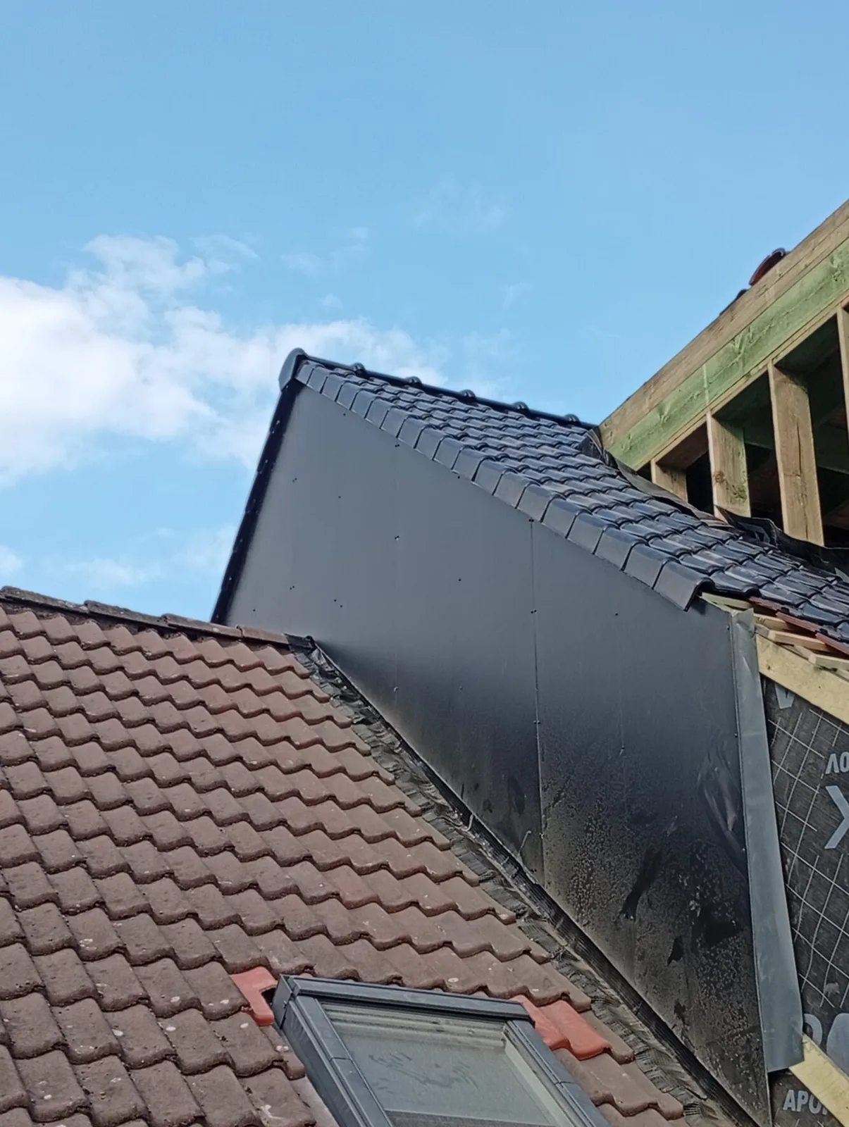Zijkant van een dakkapel met donkere pannen