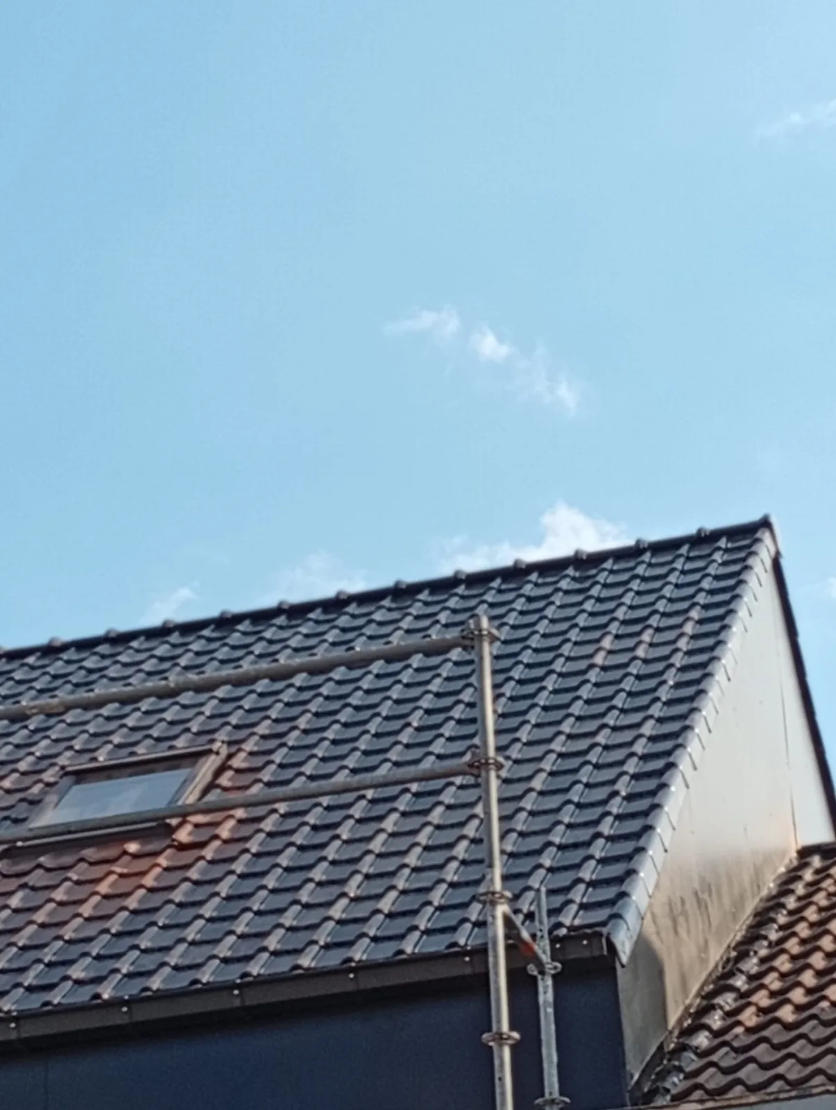 Afgewerkt hellend dak met donkere pannen en dakraam