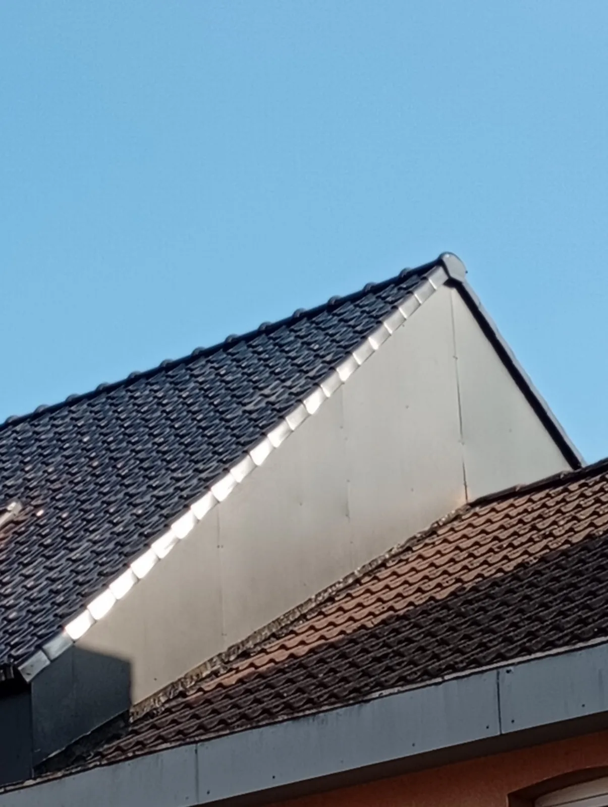 Hellend dak met donkere pannen en zinken zijaansluiting