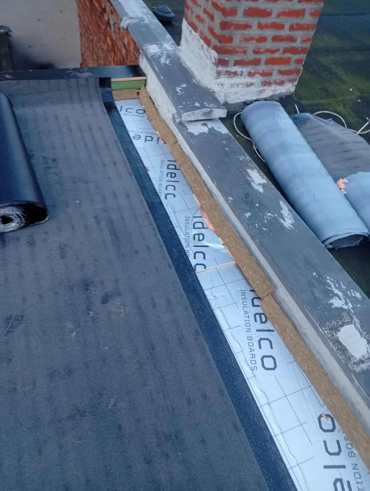 Isolatieplaten en roofing langs de opstand van een plat dak
