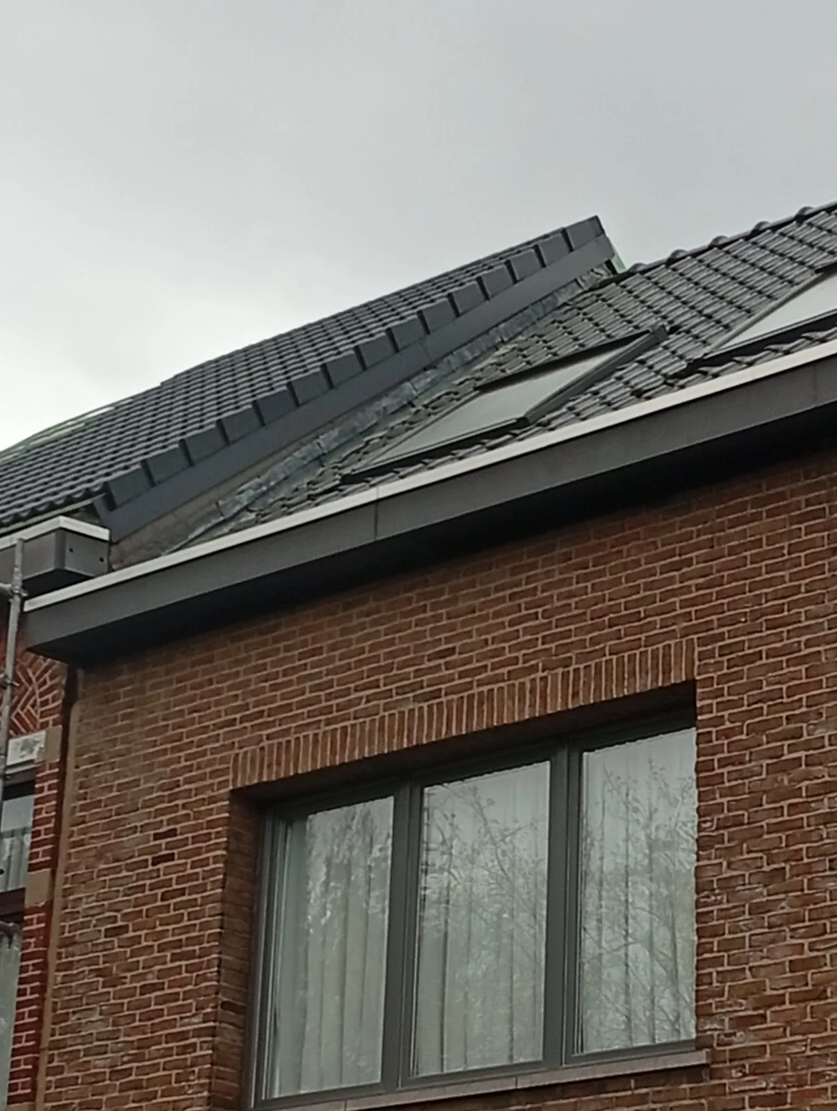 Afgewerkt pannendak boven een bakstenen gevel