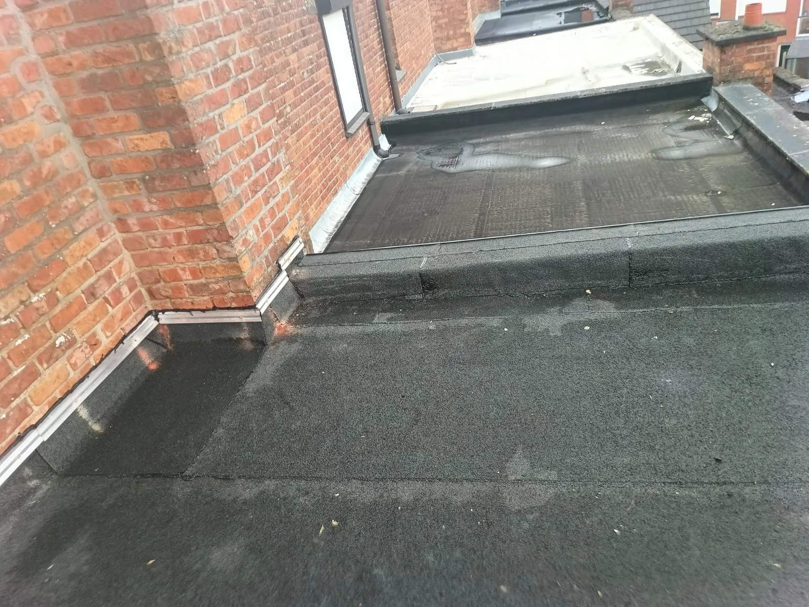 Afgewerkte roofing in de hoek tegen een gemetselde muur