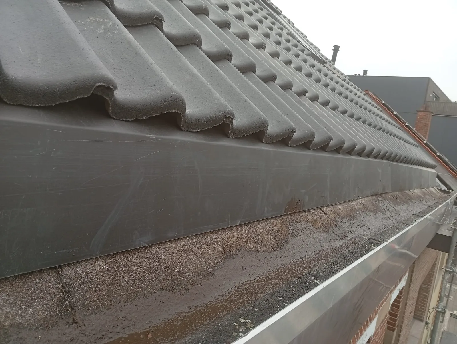 Nieuwe zinken dakgoot onder de pannen