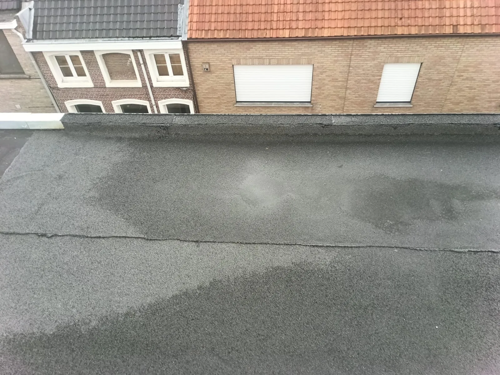 Versleten plat dak met waterplekken voor de herstelling