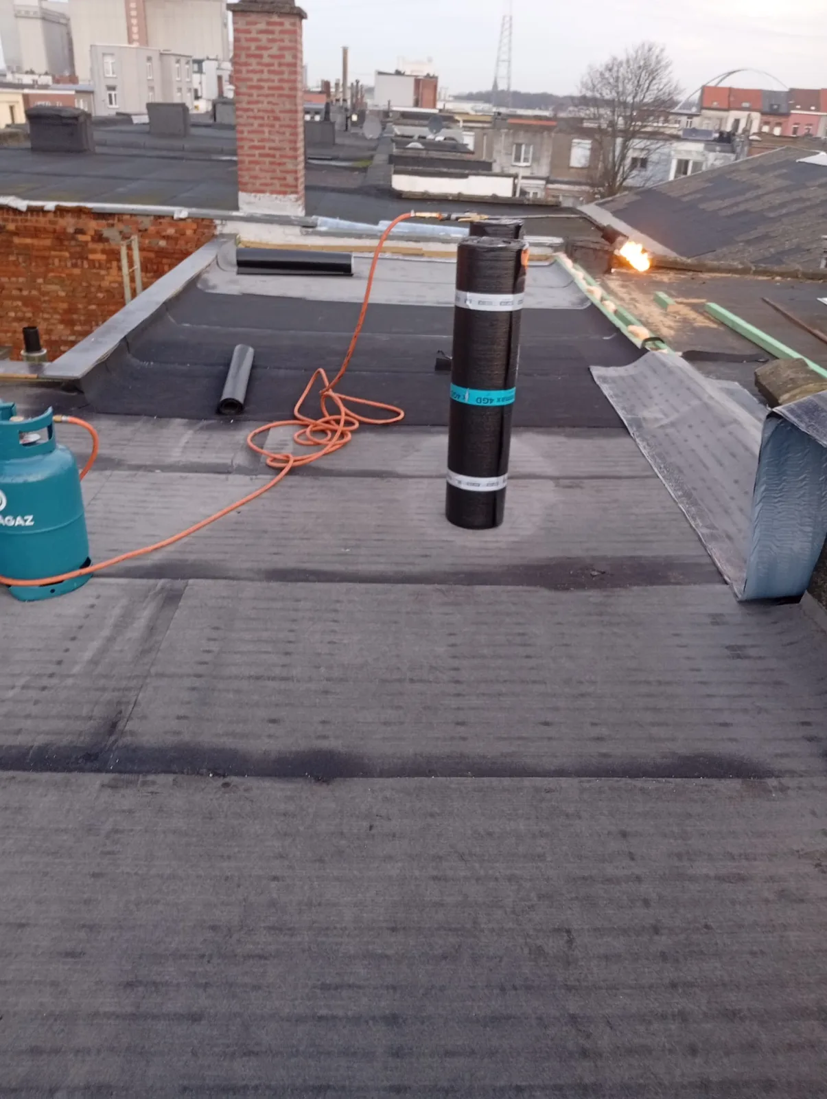 Roofing wordt gebrand op een plat dak in de stad